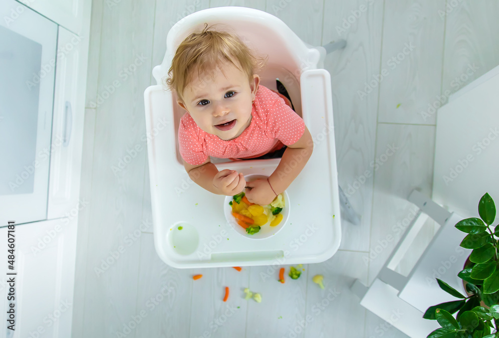 The baby eats vegetables on a chair. Selective focus. The baby eats vegetables on a chair. Selective focus.