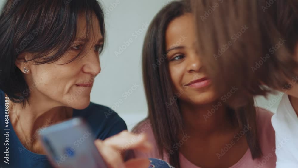 Laughing multiethnic family watching something on the phone on the bed Laughing multiethnic family watching something on the phone on the bed