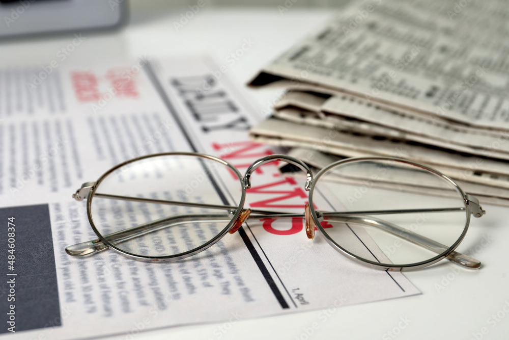 Stack of newspapers and glasses on white table, closeup Stack of newspapers and glasses on white table, closeup