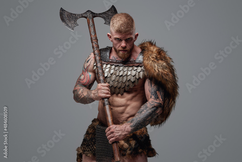 Obraz na płótnie Tattooed muscular viking holding two handed axe on his shoulder
