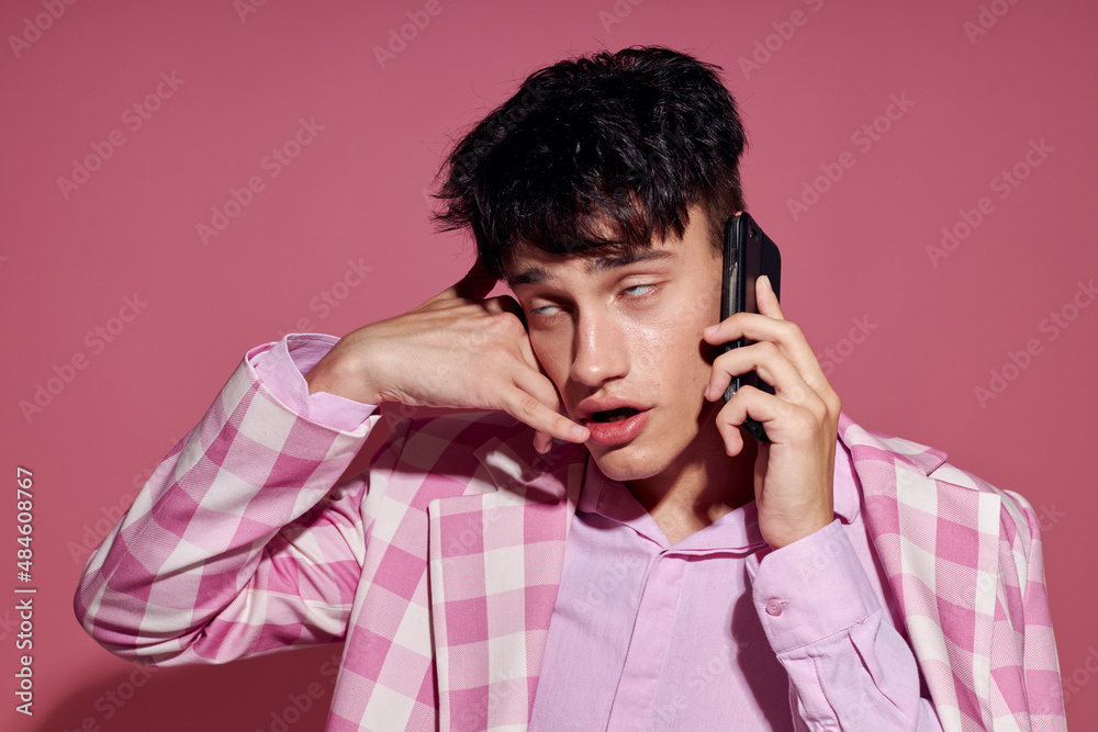 A young man with a phone in hand pink blazer fashion elegant style isolated background unaltered A young man with a phone in hand pink blazer fashion elegant style isolated background unaltered