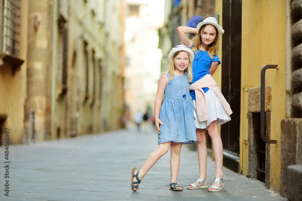 Young girls exploring beautiful medieval streets of Lucca city, known for its intact Renaissance-era city walls and well preserved historic center. Tuscany, Italy.