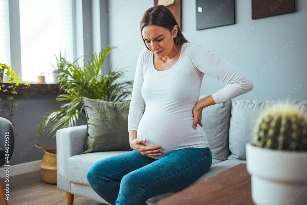 The woman feels stomach pain while working in the office, her hands