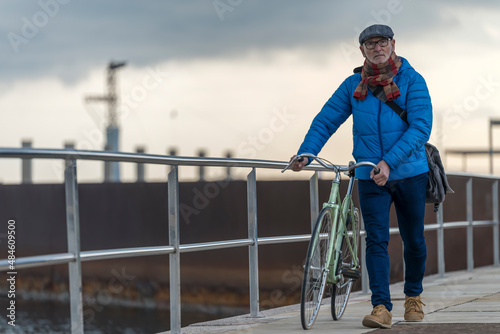 Portrait senior man walking with his bicycle next to the sea