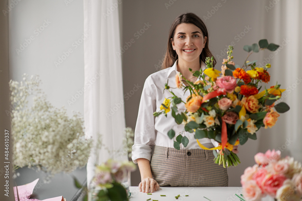 people, gardening and floral design concept - happy smiling woman or floral artist with bunch of flowers at home