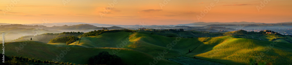 Stunning morning view of fields and farmlands with small villages on the horizon. Rural landscape of rolling hills, curved roads and cypresses of Tuscany, Italy.