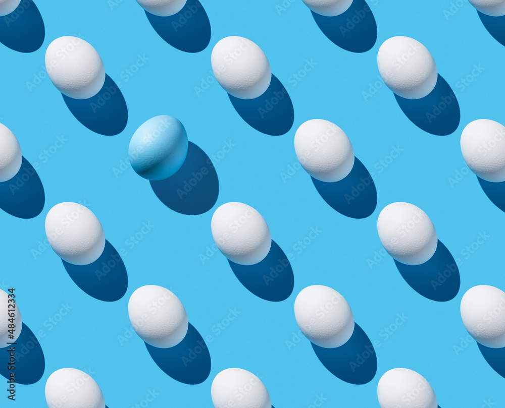 White and blue eggs with a hard shadow on a blue background