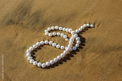 Pearl beads lie on the sand in the water of the bay