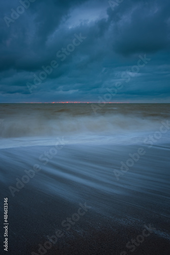 The sea wave is a blurry movement. A storm on a sandy beach. Huge waves at long exposure. Atmospheric natural background. The concept of bad weather, heavy rains, hurricane wind. Abstract Ocean