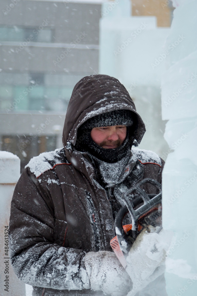 The sculptor cuts a figure from an ice block with a gasoline saw The sculptor cuts a figure from an ice block with a gasoline saw