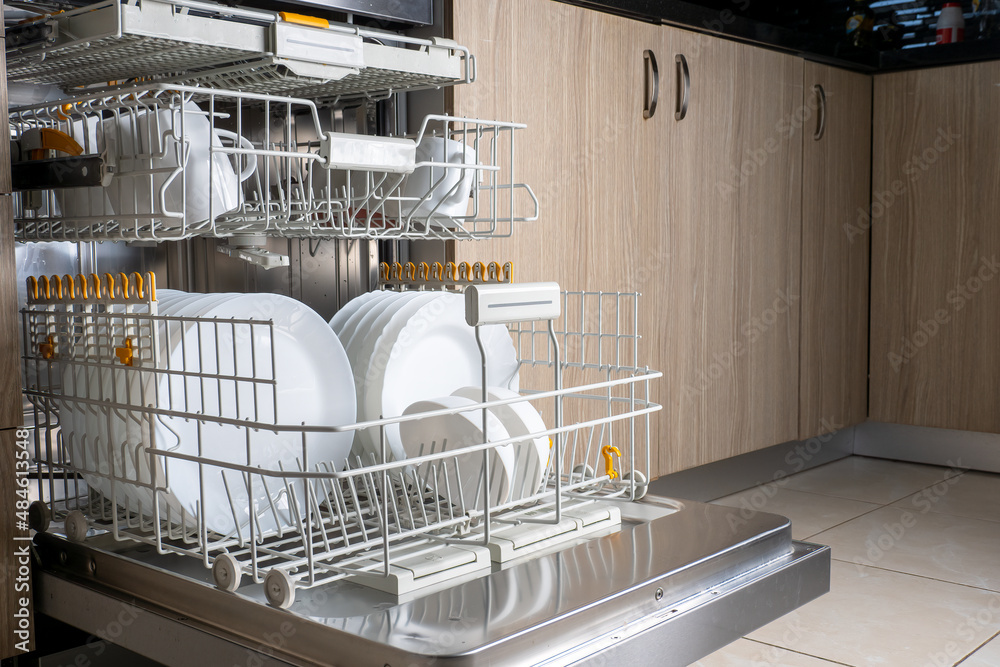 Shelves popped out of the dishwasher, filled with clean white dishes