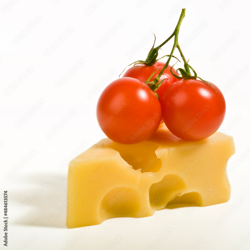 Bunch of fresh cherry tomatoes placed on a slice of Swiss cheese.