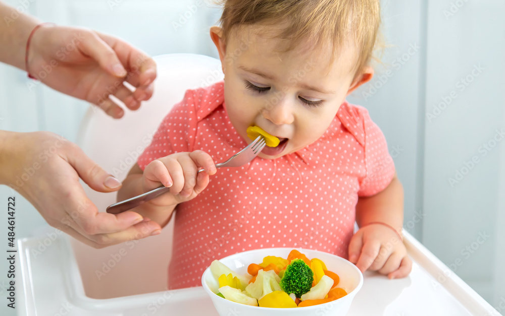 The baby eats vegetables on a chair. Selective focus. The baby eats vegetables on a chair. Selective focus.