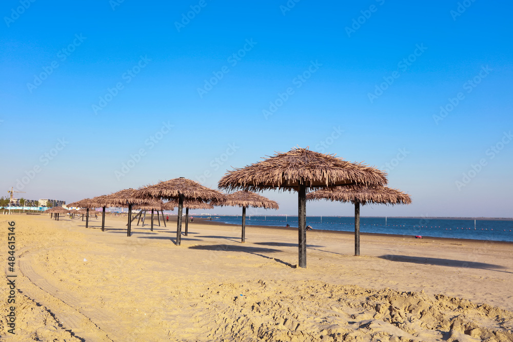 Fototapeta premium Umbrella from the sun with a roof of palm leaves on a background of the sea on a sunny day.