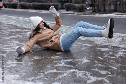 Young woman fallen on slippery icy pavement outdoors photo