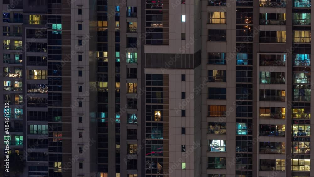 Apartment windows of a glazed skyscraper glow at night with city lights reflection aerial timelapse. Apartment windows of a glazed skyscraper glow at night with city lights reflection aerial timelapse.