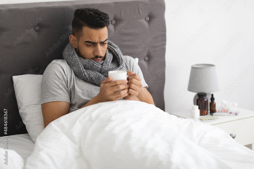 Obraz premium Cold And Flu. Portrait Of Sick Arab Man Drinking Tea In Bed