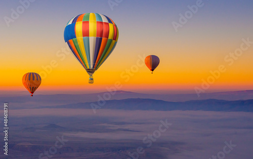 Hot air balloons in the sky during sunrise. Flying over the valley at Cappadocia, Anatolia, Turkey. Volcanic mountains in Goreme national park. Colourful hot air balloons.