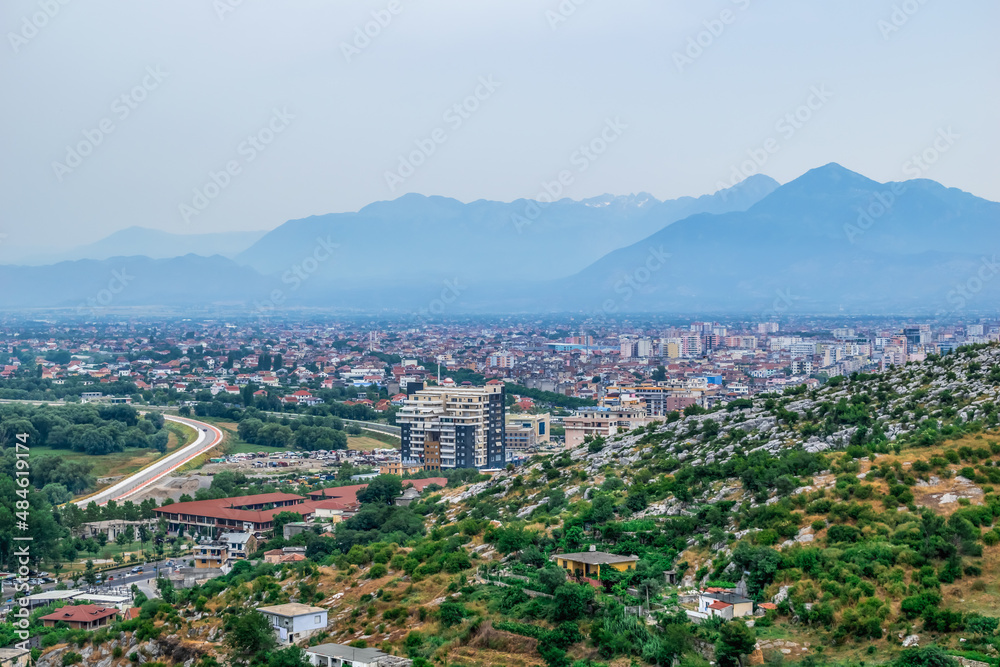 Panorama of Shkoder in the valley against the backdrop of mountain silhouettes in Albania - view from above. Albanian town city skyline - view from hill