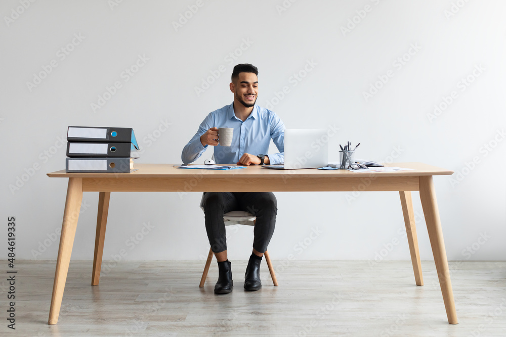 Arab man using laptop sitting at desk in office Arab man using laptop sitting at desk in office