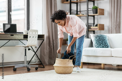 household, home improvement and cleaning concept - happy smiling young woman with blanket and wicker basket sitting on floor © Syda Productions