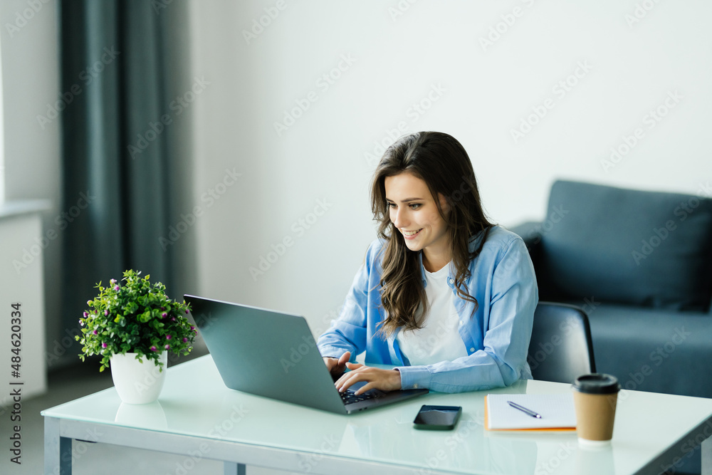 Concentrated young businesswoman working on laptop in bright modern office Concentrated young businesswoman working on laptop in bright modern office