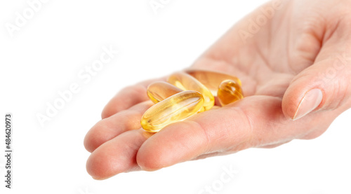 Close up of hand holding Omega 3 soft gel capsules on white background. Copy space