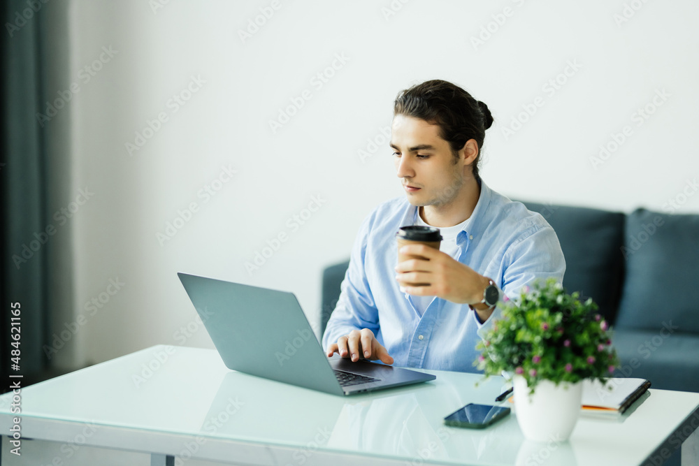 Happy man working on laptop at home, drinking coffee Happy man working on laptop at home, drinking coffee