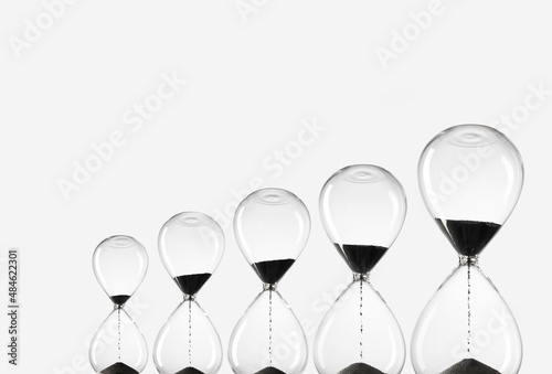 Hourglasses of various sizes on white background. Black Sand in hourglasses. Time is money. 