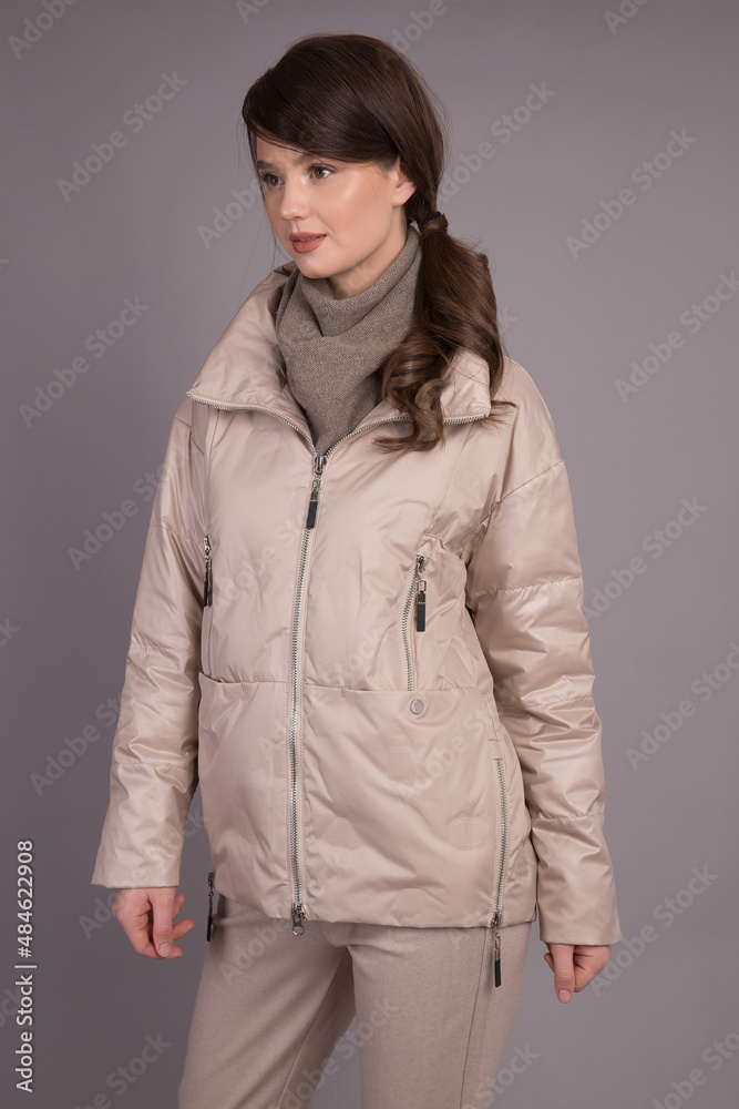 A young girl model posing at the camera demonstrates clothes in different positions.Shooting in a clothes studio on a gray background showing a model. A young girl model posing at the camera demonstrates clothes in different positions.Shooting in a clothes studio on a gray background showing a model.