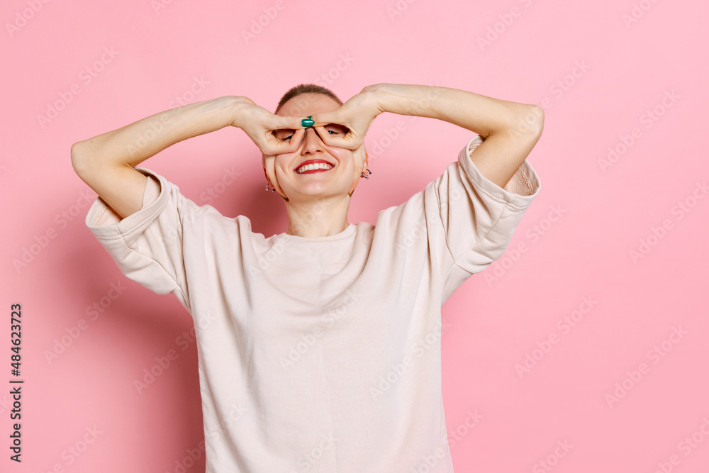 Half-length portrait of young woman, student with short hair in white t-shirt isolated on pink background. Concept of emotions, studying, ad Half-length portrait of young woman, student with short hair in white t-shirt isolated on pink background. Concept of emotions, studying, ad