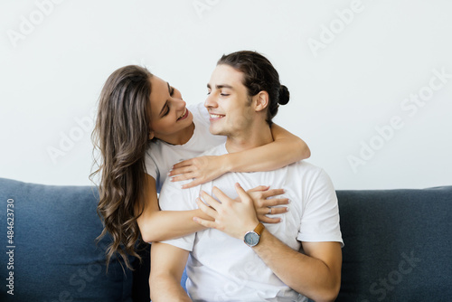 Portrait of young loving couple resting on a couch together at home and hugging
