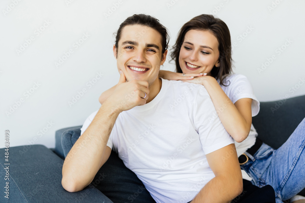 Happy young couple of man and woman embracing look at each other sitting on couch in living room. Happy young couple of man and woman embracing look at each other sitting on couch in living room.