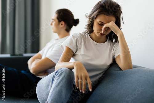 Beautiful young couple is having a quarrel while sitting on sofa at home photo