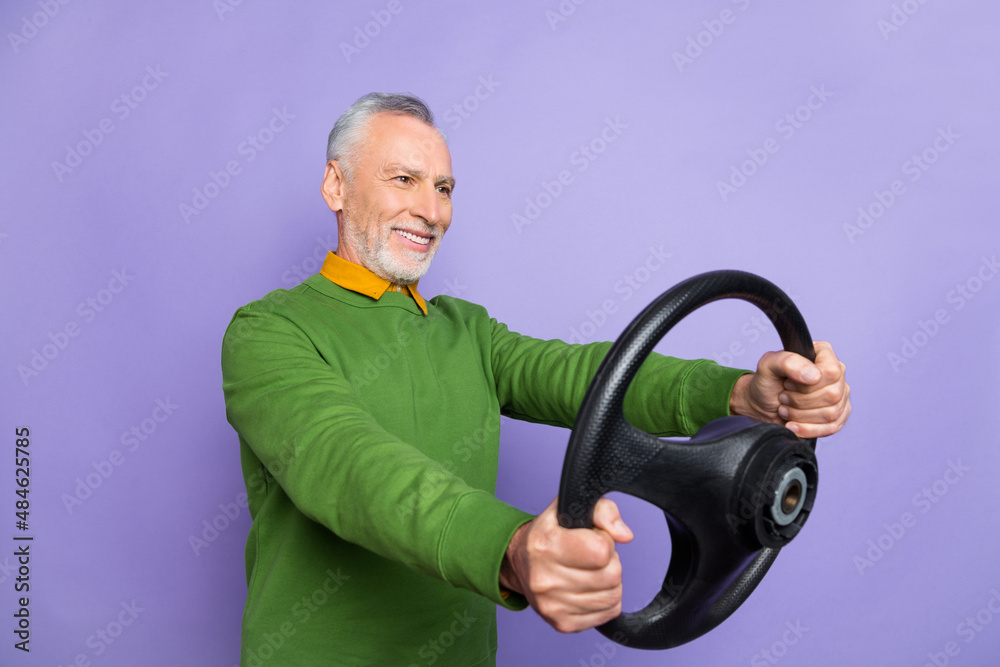 Photo of good mood retired man wear green sweater riding vehicle empty space isolated violet color background Photo of good mood retired man wear green sweater riding vehicle empty space isolated violet color background