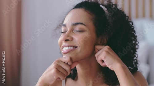 Self ckin care. Young black woman doing self facial massage. Finger massage for an elastic jawline photo