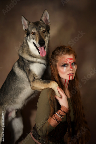 Fotografie, Obraz Female viking  with painted face and grey wolf on brown background
