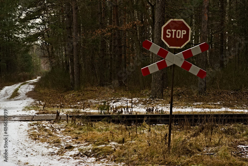 Znak stop i krzyż świętego Andrzeja przed przejazdem kolejowym w lesie zimą . Tory kolejowe , leśna droga śnieg. photo