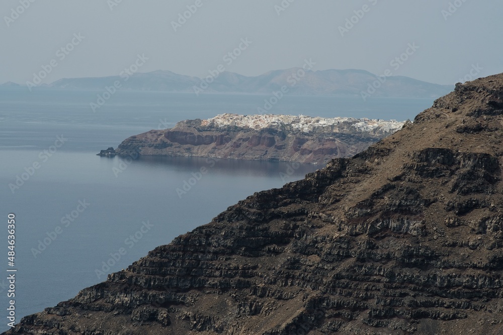 View of rocks and cliffs and the picturesque village of Oia in the background in Santorini Greece 