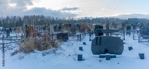 Snowing in the public cemetery. Traditional graveyard in winter under snow. Tombstone on the necropolis.