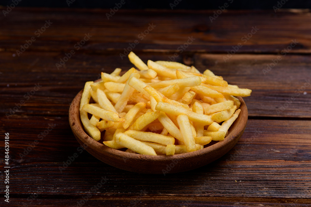 french fries in wooden bowl. French fries in a wooden bowl on a wooden background. french fries in wooden bowl. French fries in a wooden bowl on a wooden background.