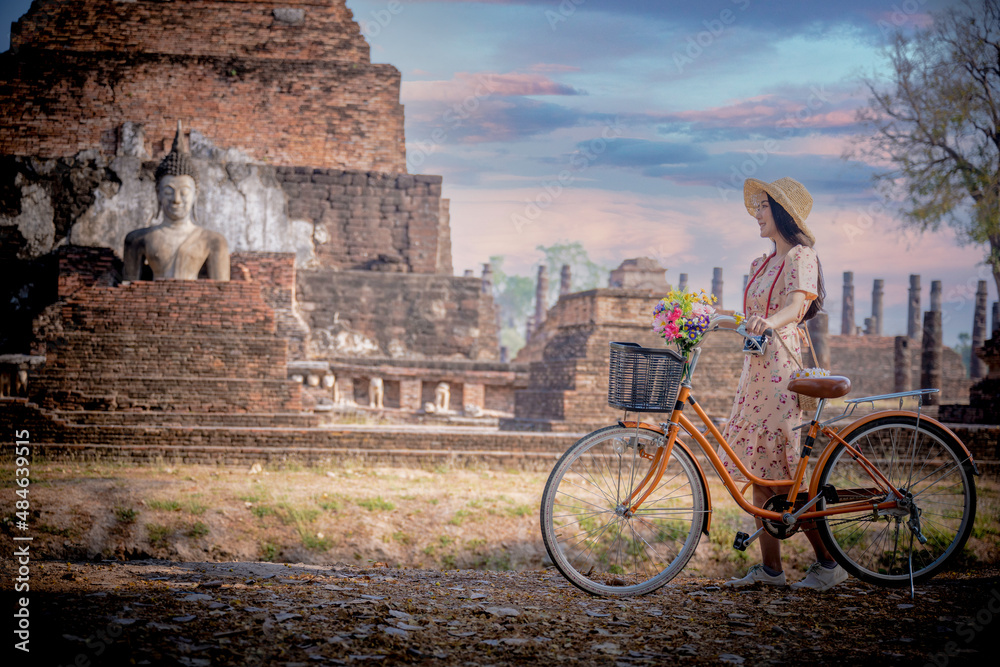 Woman traveler tourist in action of enjoy riding retro style classic bicycle around the historic cenvisiting old fashion period in vacation long weekends occasion,