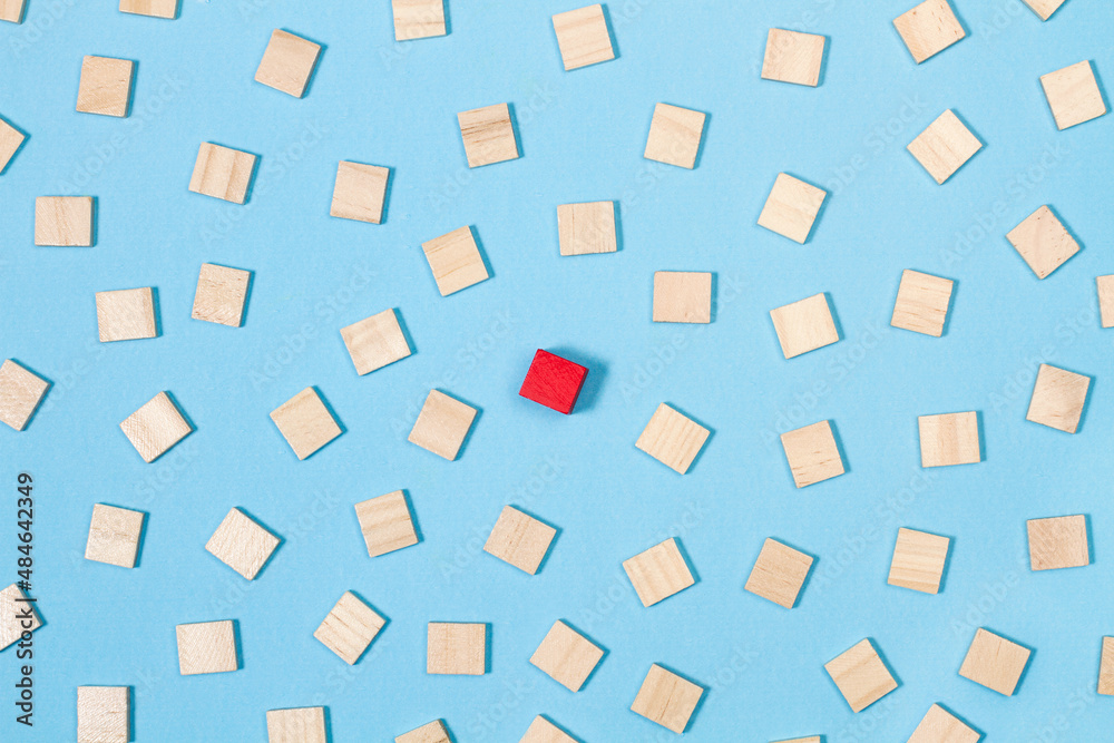 Bloque de madera roja sobresaliendo del grupo de bloques de madera sobre fondo azul. Vista superior. Concepto: Liderazgo, conceptos de puntos de vista divergentes 