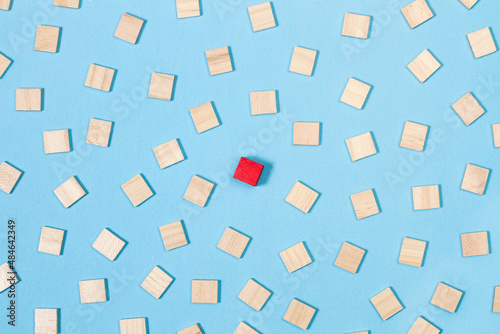 Bloque de madera roja sobresaliendo del grupo de bloques de madera sobre fondo azul. Vista superior. Concepto: Liderazgo, conceptos de puntos de vista divergentes 