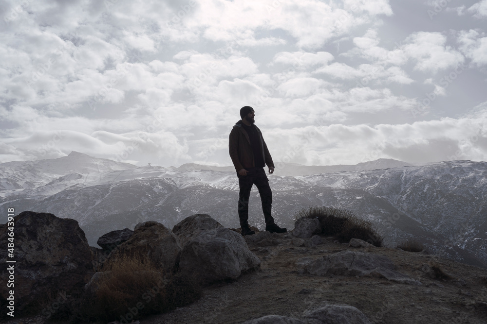 Fototapeta premium Silueta de hombre en una montaña mirando al horizonte mientras señala