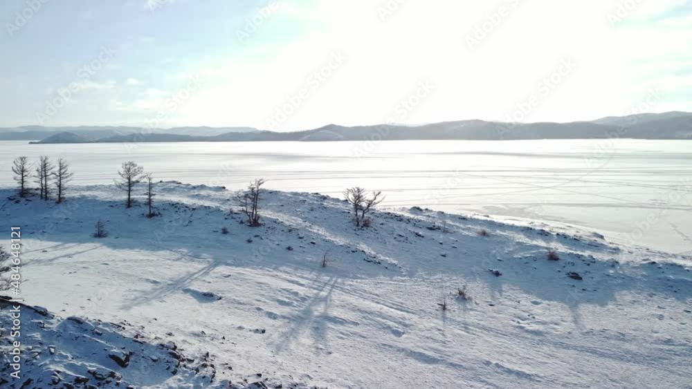 Winter landscape of snow-covered Lake Baikal with rocks and hills on a sunny frosty day. Shooting from a drone Winter landscape of snow-covered Lake Baikal with rocks and hills on a sunny frosty day. Shooting from a drone
