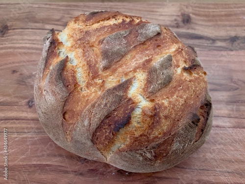 Baked sourdough bread sitting on a wooden butchers block