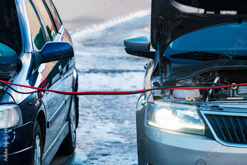 Charging a car battery in winter. Help on the road. Close-up. Connecting high voltage wires to the car battery. Resuscitation of the car in severe winter conditions. photo