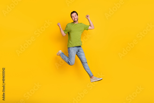 Full body photo of young man jump up rejoice victory fists hands goal awesome isolated over yellow color background