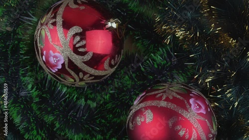 Two big red colored Christmas balls rotate on green fluffy clinquant background. Holiday and celebration conception. photo